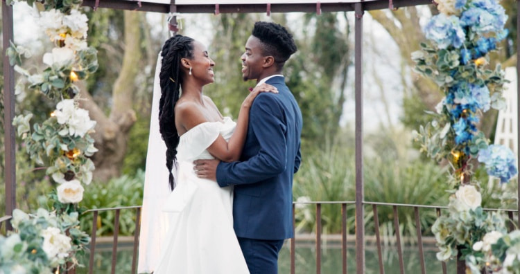 A bride and groom smile at each other under a gazebo