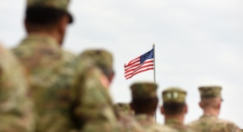Soldiers stand in a line looking at an American flag