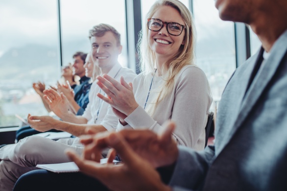 A few colleagues sit together and clap after a presentation 