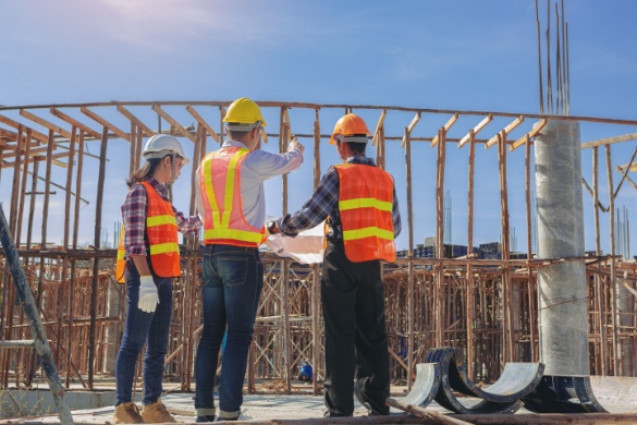 Three construction workers oversee construction on a busy worksite